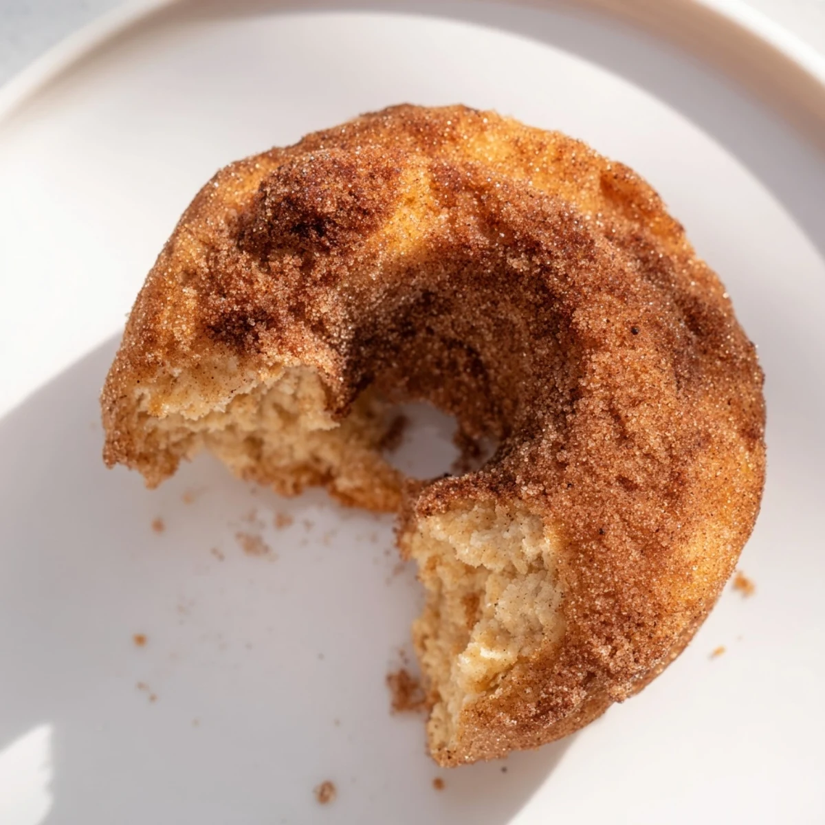 Eight golden brown Air Fryer Cinnamon Sugar Donuts arranged on a rustic wooden serving platter alongside a steaming mug of coffee.  