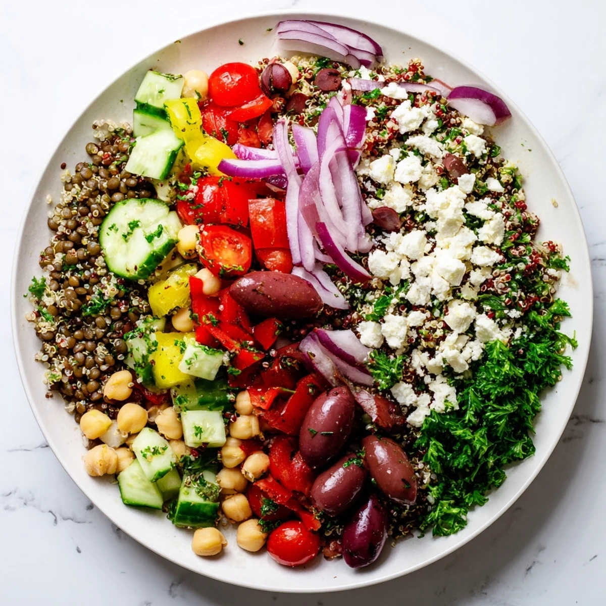 Freshly tossed Greek Power Salad brimming with quinoa, lentils, chickpeas, and colorful veggies.  