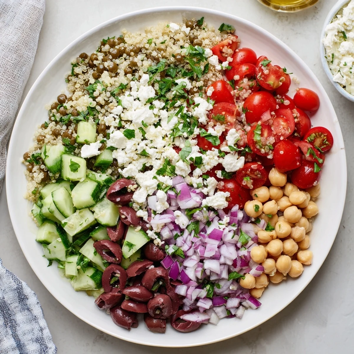 Vibrant Greek Power Salad topped with feta and olives, served in a rustic white bowl.