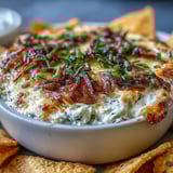 Golden-brown baked smoked Gouda and onion dip offers creamy texture and smoky aromas, paired with crisp vegetables for dipping.