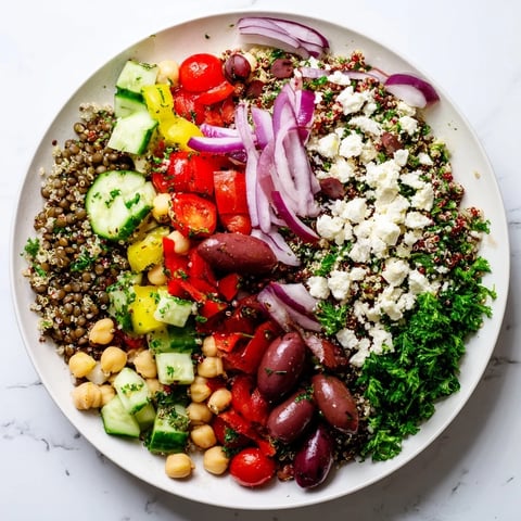 Freshly tossed Greek Power Salad brimming with quinoa, lentils, chickpeas, and colorful veggies.  