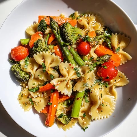 Rainbow Veggie Pasta Primavera with al dente bow-tie pasta and vibrant green asparagus, served warm in a white bowl.