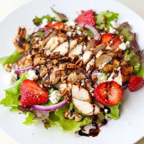 Juicy grilled chicken slices, sliced strawberries, and crumbled goat cheese on mixed greens, drizzled with a glossy honey balsamic glaze.