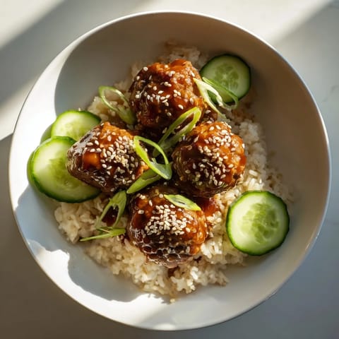 A close-up of delicious teriyaki meatball bowls, showing savory sauce coating the meatballs ready to enjoy.