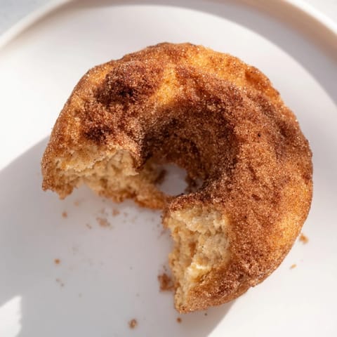 Eight golden brown Air Fryer Cinnamon Sugar Donuts arranged on a rustic wooden serving platter alongside a steaming mug of coffee.  