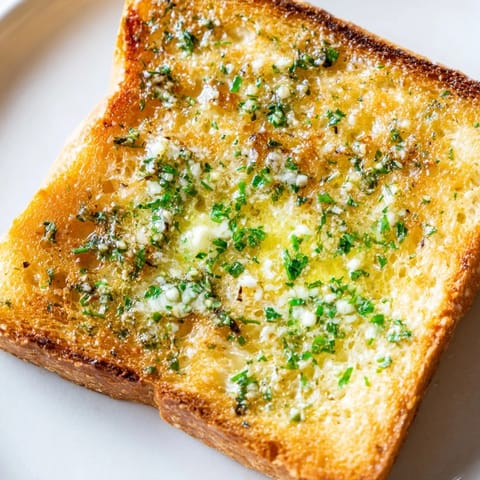 Fragrant herb butter melts into crispy crusty bread slices, creating a perfect savory snack or appetizer.  