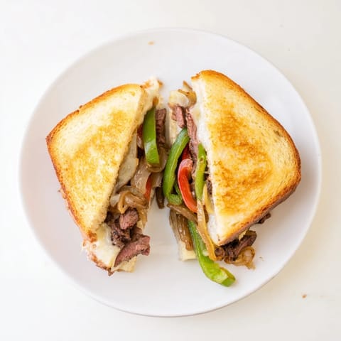 Philly cheesesteak grilled cheese on sourdough, served with a side of crispy fries.