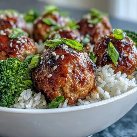 Golden Honey Garlic Turkey Meatballs glisten with glaze over fluffy rice and vibrant green broccoli florets.