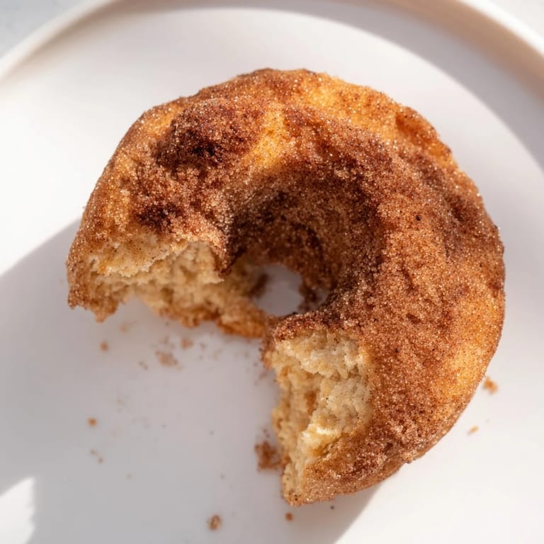 Eight golden brown Air Fryer Cinnamon Sugar Donuts arranged on a rustic wooden serving platter alongside a steaming mug of coffee.  