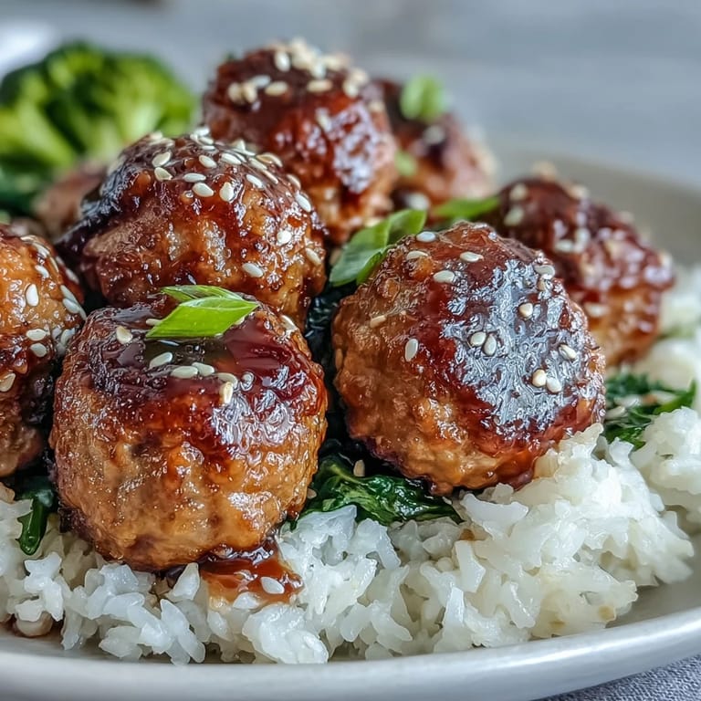 Steam rises from Honey Garlic Turkey Meatball Bowls with glazed turkey meatballs, rice, and broccoli florets on a plate.