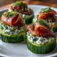 Savory smoked salmon cucumber bites, topped with dill cream cheese on a platter.