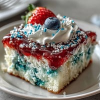 Memorial Day Red White Blue Poke Cake with vibrant gelatin swirls and creamy whipped topping, decorated with festive sprinkles for a patriotic dessert.